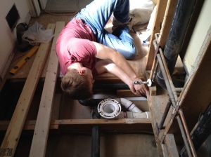 Subfloor gone! Jim working on the waste pipes.
